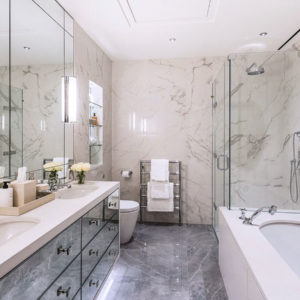 Custom designed double vanity and bathtub surround clad with Frosty Carrina quartz stone